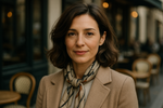 Portrait of a 40-year-old French woman, elegant and natural beauty, light makeup, soft smile, medium-length wavy brown hair, wearing a chic Parisian outfit (neutral colors, stylish scarf), photographed in natural daylight, background blurred with a subtle Paris street café vibe, realistic, high detail, cinematic lighting.